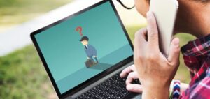 homem mexendo com uma mão no notebook e a outra mão falando no celular na rua